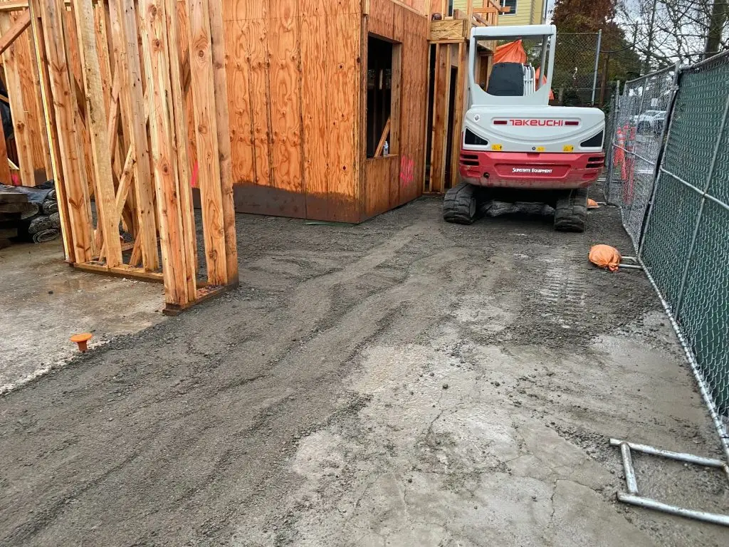 Construction site with wooden framing and Takeuchi mini excavator on freshly laid gravel surface, illustrating excavation and site preparation services by Arc Excavation in Jacksonville.