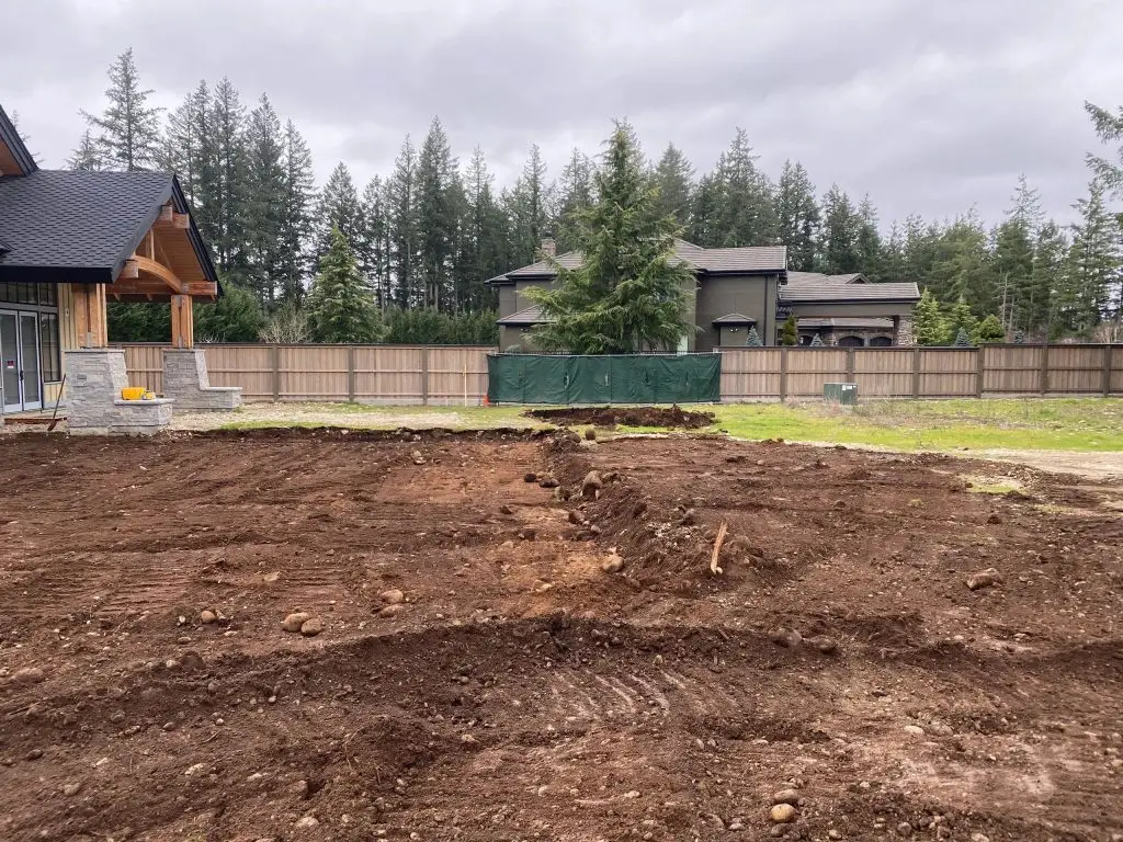 Excavated land preparation site showing cleared dirt area and surrounding residential structures in Jacksonville, highlighting excavation and grading services.