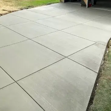 Freshly installed concrete driveway with smooth, textured surface and visible expansion joints, showcasing quality workmanship by ARC Excavation.