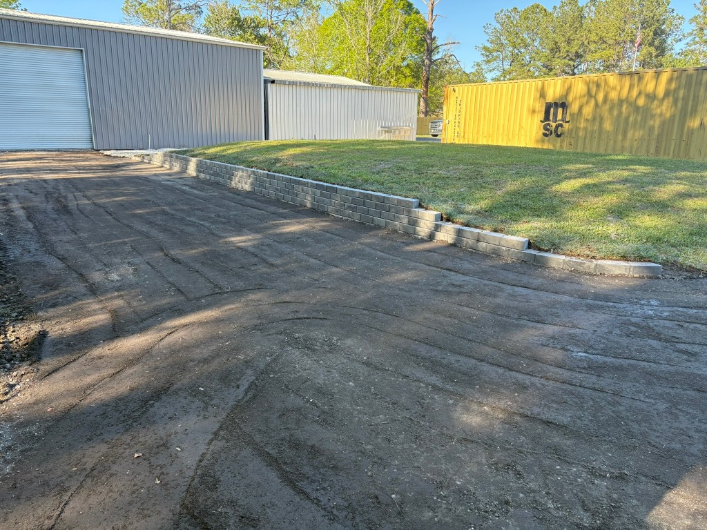 Gravel driveway installation with retaining wall, showcasing prepared surface and surrounding structures, emphasizing ARC Excavation's expertise in driveway preparation and installation.